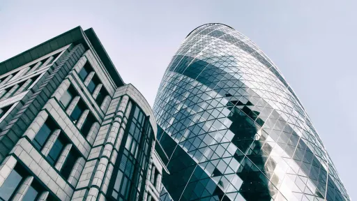 Modern glass skyscrapers photographed from below against an overcast sky