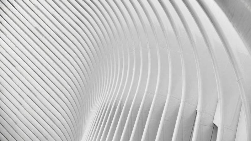 Abstract white curved architectural structure with repeating ribbed patterns creating rhythmic shadows