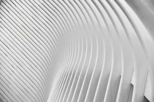 Abstract white curved architectural structure with repeating ribbed patterns creating rhythmic shadows